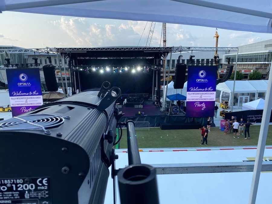 camera pointed toward an outdoor event stage in a grassy area